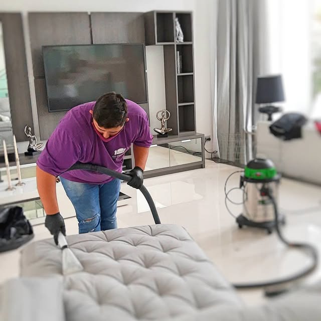 Técnico da All Cleaner higienizando um sofá claro na sala do cliente